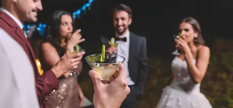 Svatebčané s drinkem v ruce si užívají venkovní svatební zábavu v noci.
